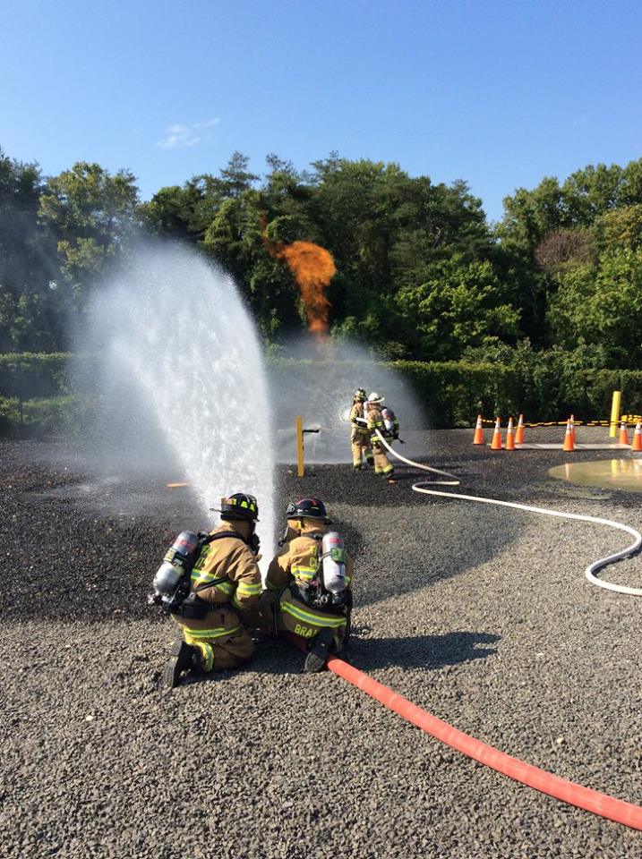 Photo of firefighters using hose lines to put water on a gas fire